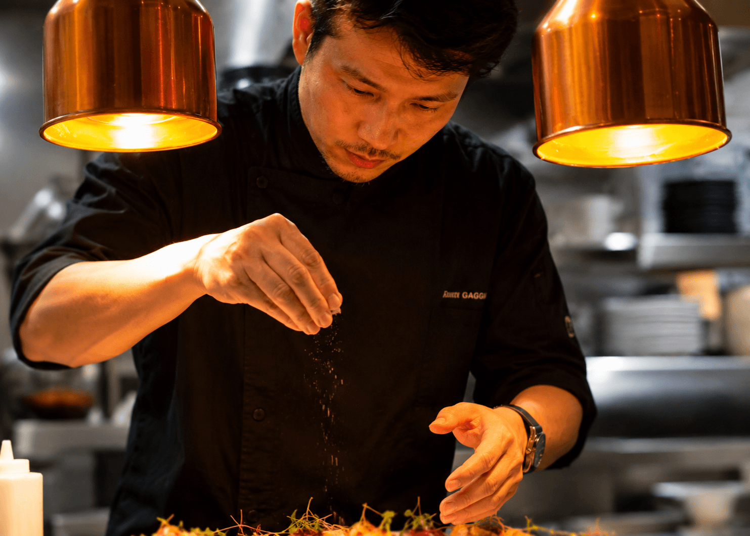 Chef preparing food under copper lamps
