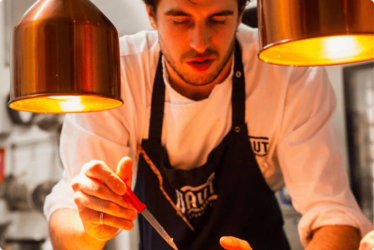 Chef preparing food under copper lamps